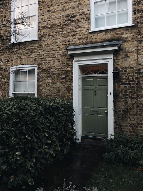 Photograph of the exterior entrance to a narrow Victorian-style house in Palmers Green, Southgate. The front door is painted a muted green with a small window at the top and a letterbox below. The doo